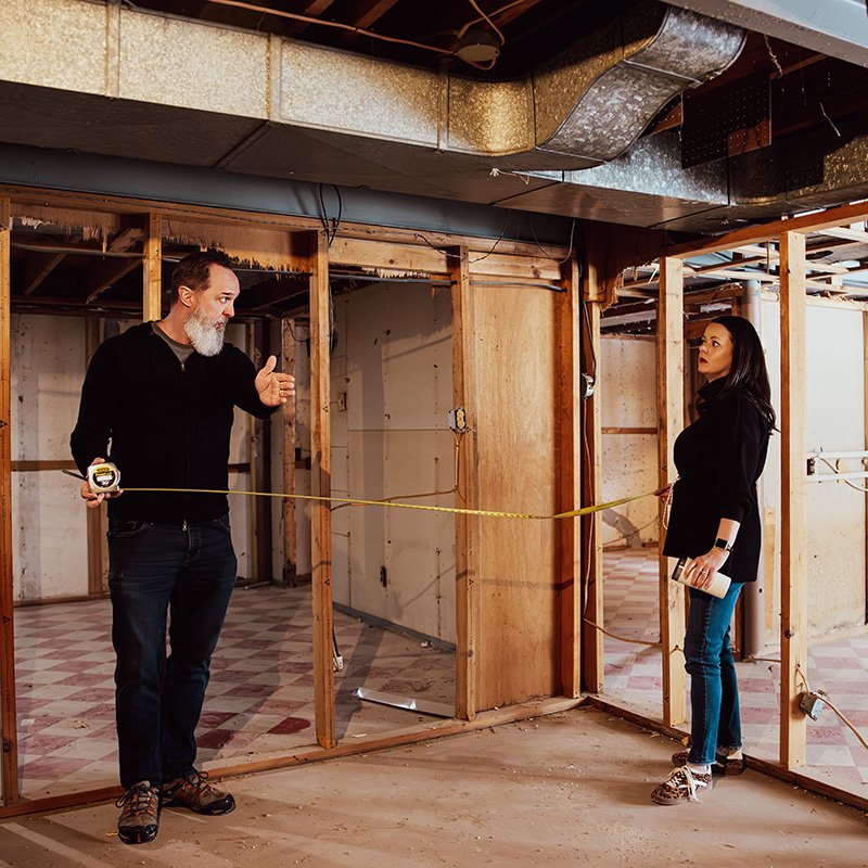 Matt and Rebekah Copeland measuring wall framing during a property renovation